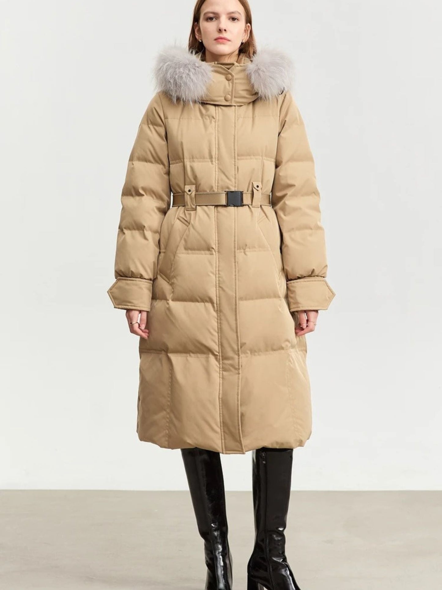 Beige coat front view, fully zipped. The model stands straight with arms down, wearing black leggings and boots