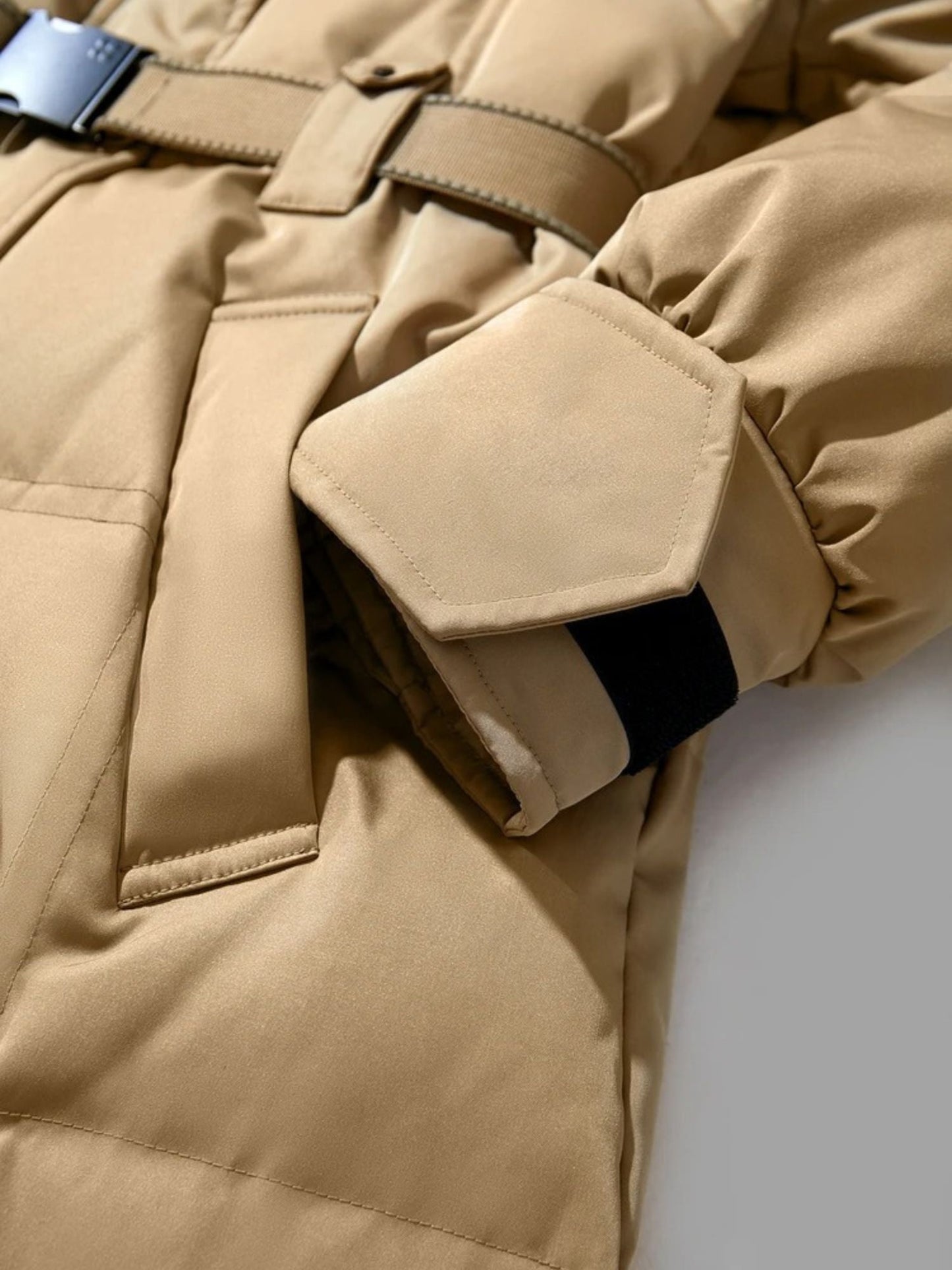 Close-up of the beige coat’s side pocket and belt, with emphasis on the stitching and pocket flap