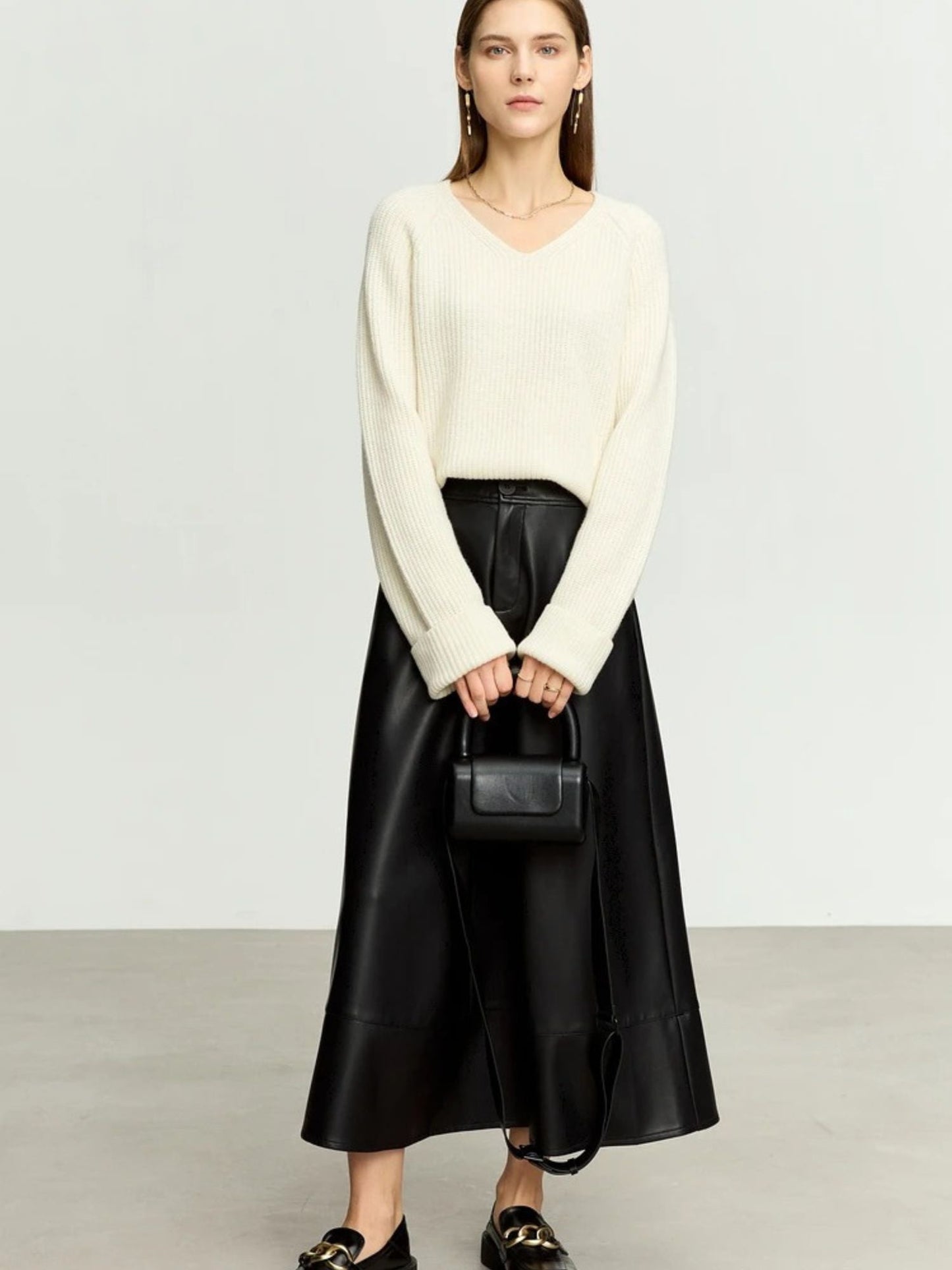 Black faux leather midi skirt styled with white sweater and black handbag