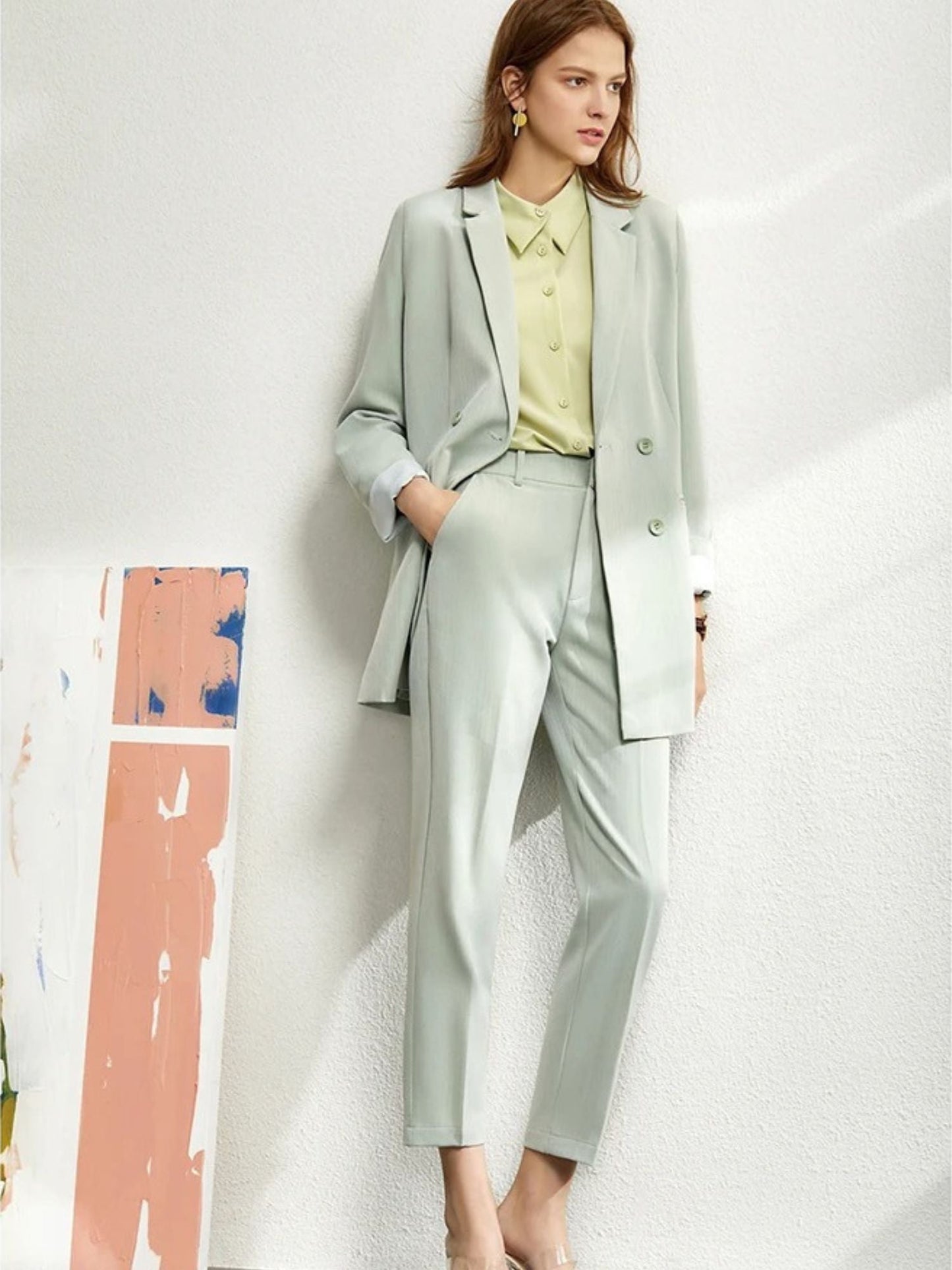 Woman in a light mint green oversized blazer and trousers, paired with a yellow blouse