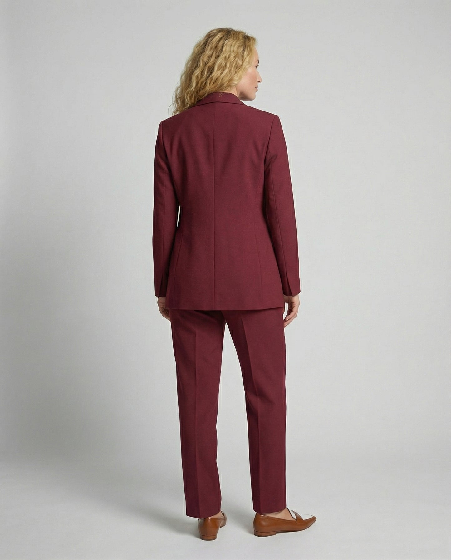 Woman wearing a burgundy suit against a plain background