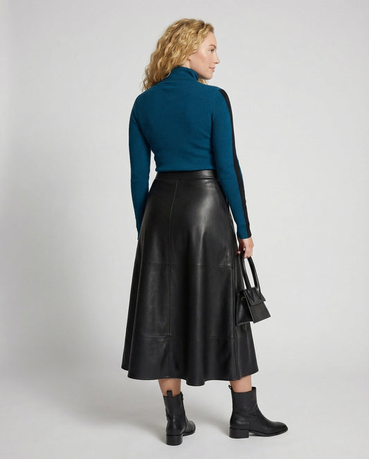 Woman wearing a teal top and black leather skirt on a white background