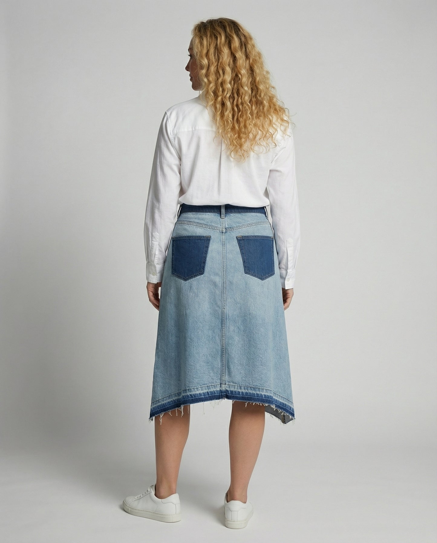 Person wearing a denim skirt with a plain background