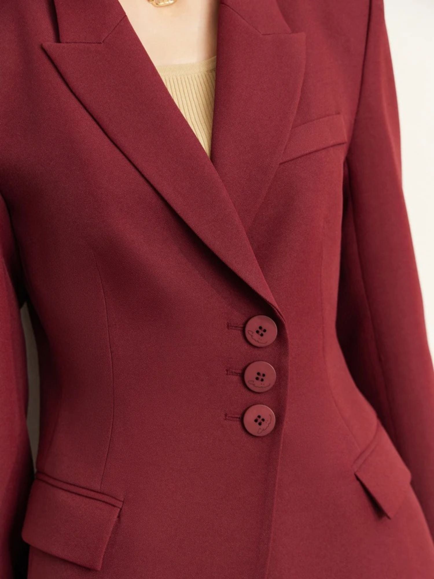 Close-up of burgundy blazer showing button details and chest pocket