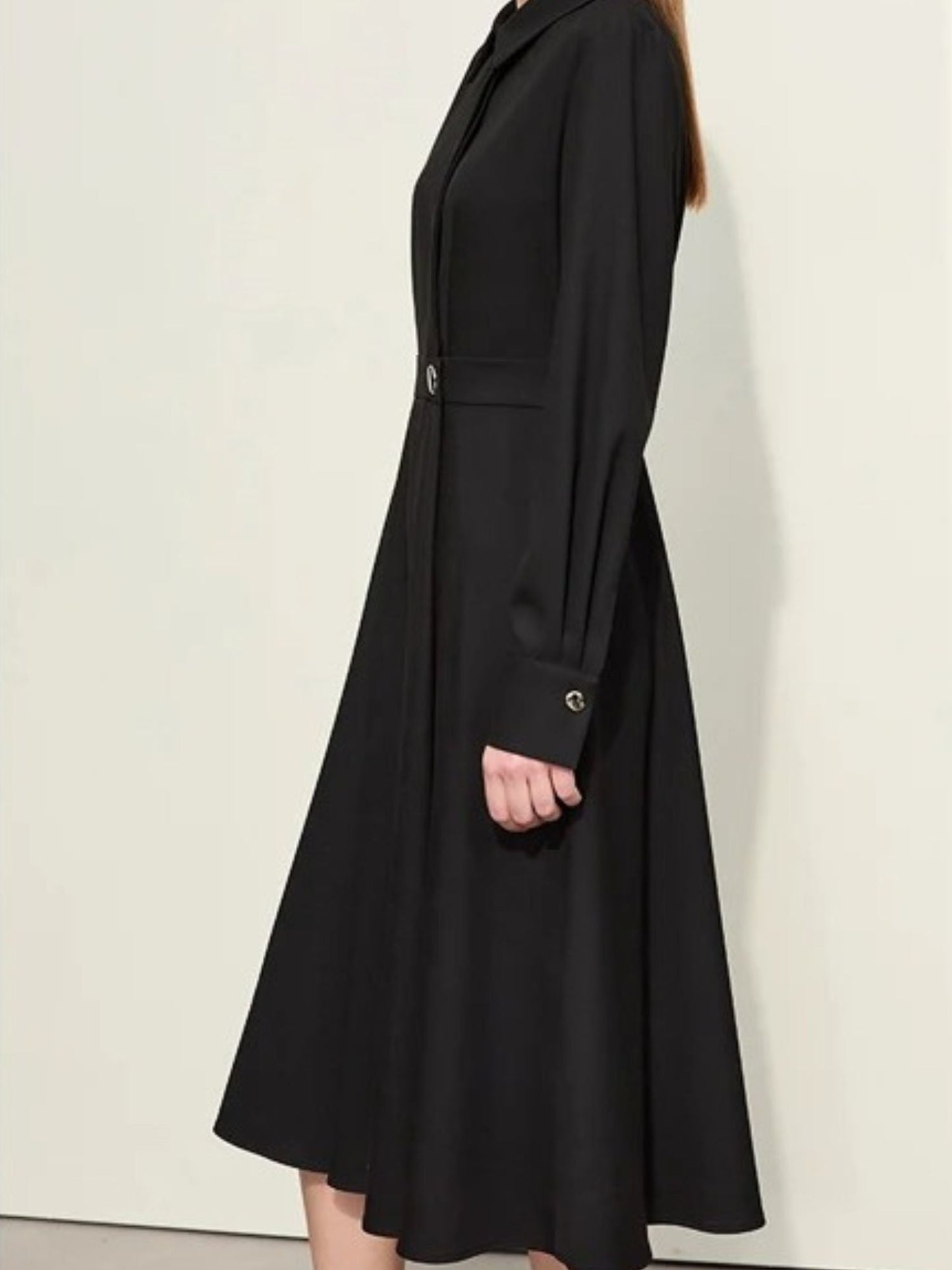 Side view of black long-sleeve midi shirt dress showing fitted waist and flared skirt
