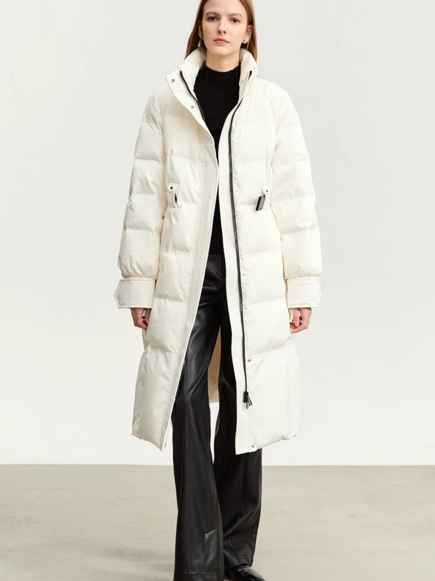 Three-quarter view of the white coat worn open, paired with dark trousers. The collar is turned slightly out