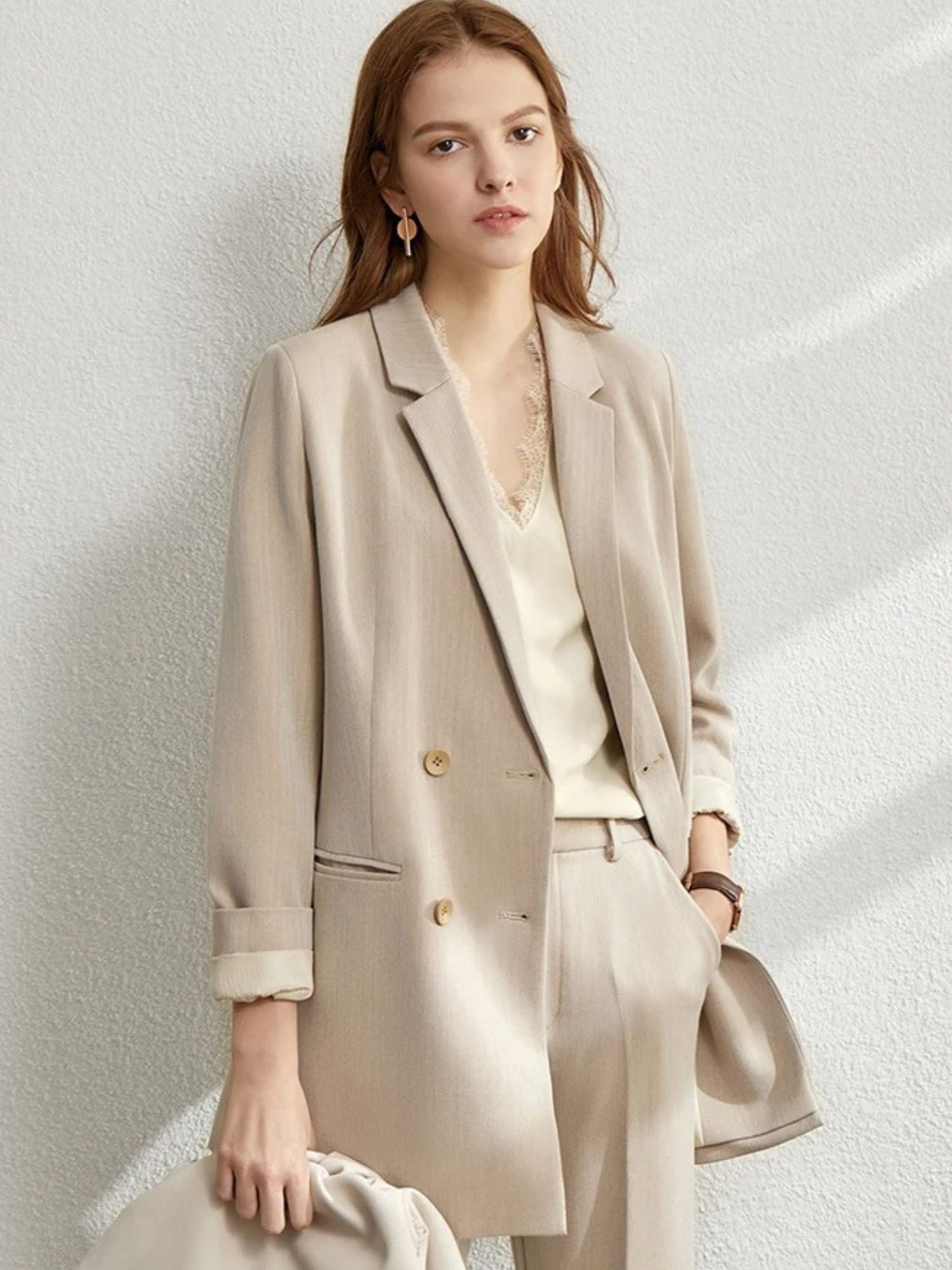 Woman in a beige oversized blazer and matching trousers, paired with a pale blouse and a taupe crossbody bag