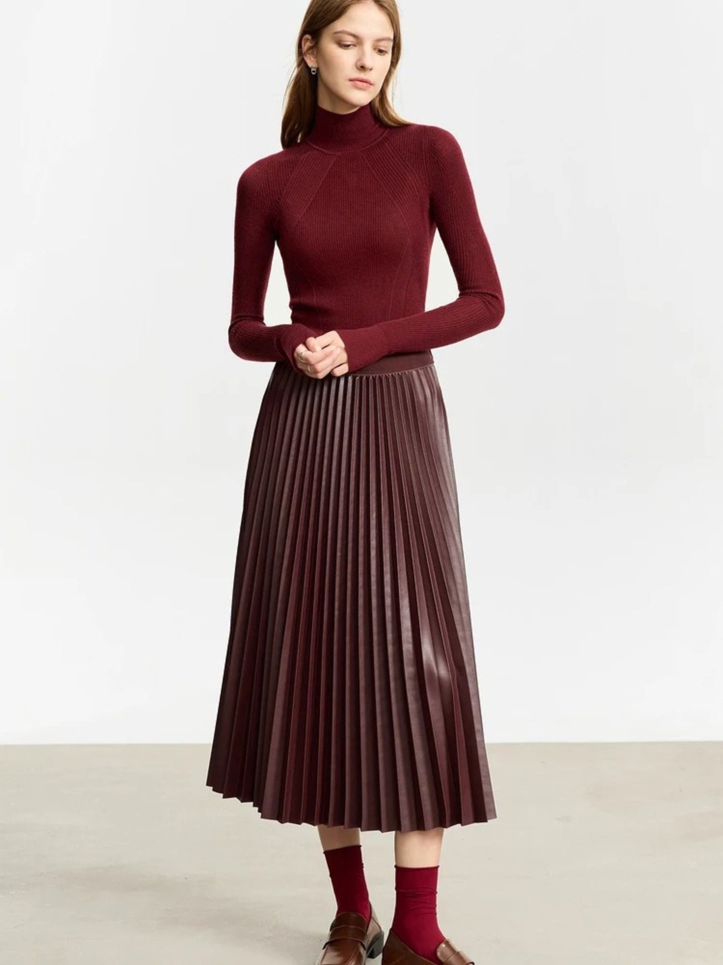 Front view of burgundy faux leather pleated midi skirt styled with burgundy long-sleeve top