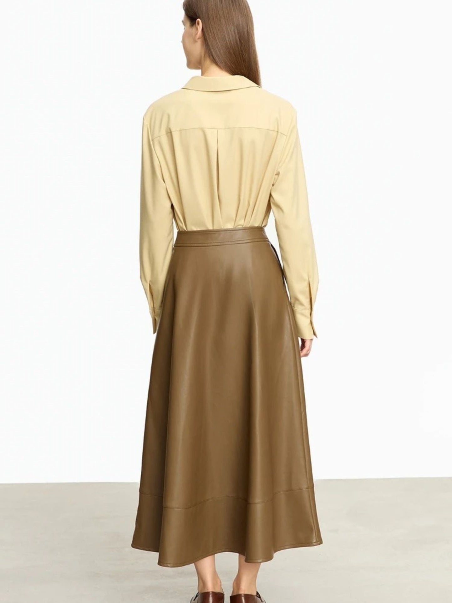 Back side view of brown faux leather midi skirt showing smooth finish