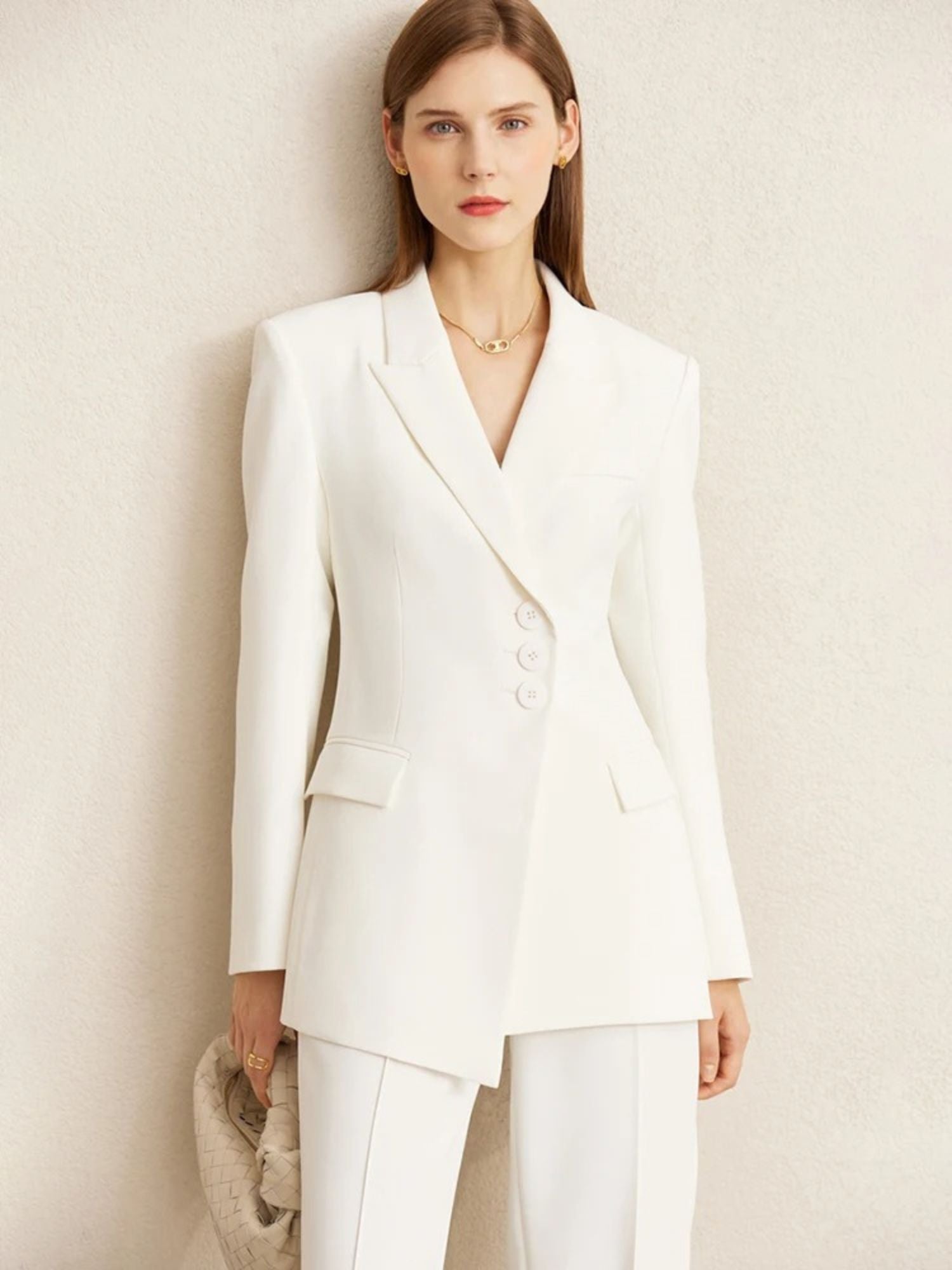 Another angle of the woman in a white pantsuit with a V-neckline blazer and pointed heels