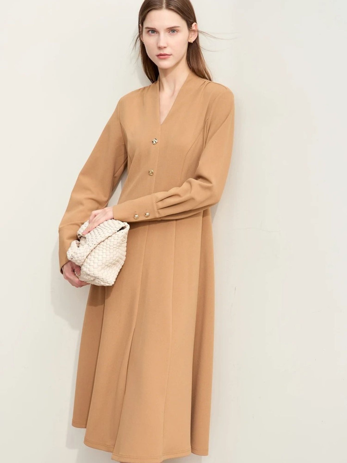 Camel-colored long-sleeve midi dress with button-front closure and relaxed fit, paired with white handbag and neutral shoes