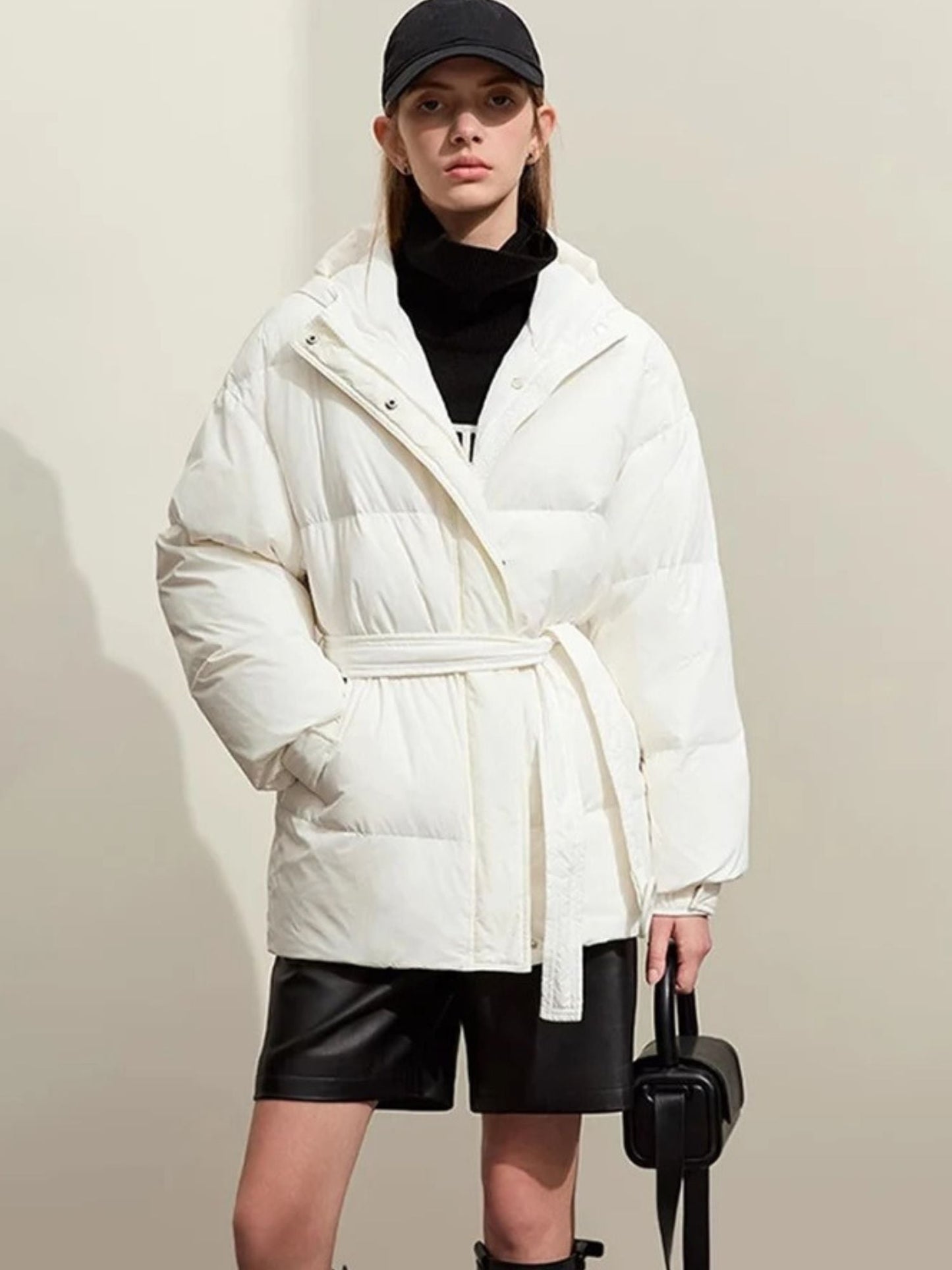 A slight three-quarter view of the white puffer. The model is standing naturally, highlighting the curved seams and fit of the jacket