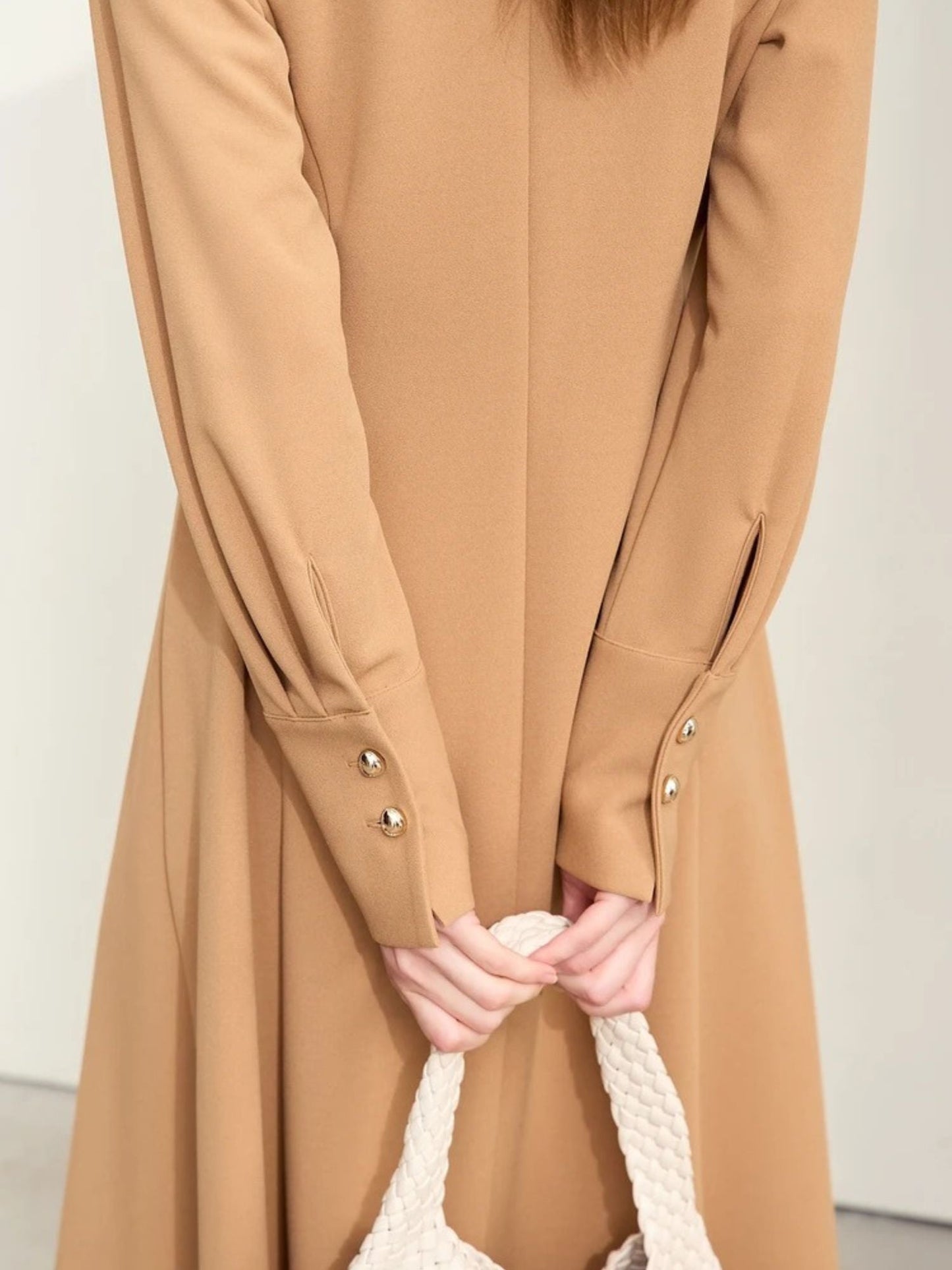 Close-up of camel midi dress sleeve showing gold button details