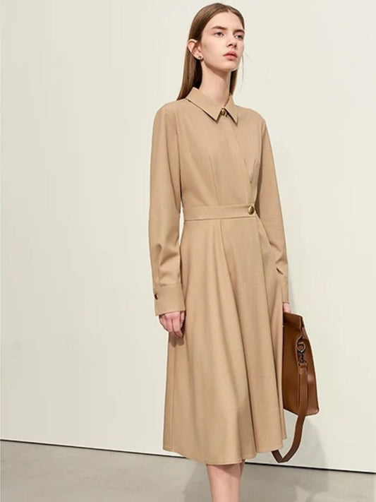 Women's beige long-sleeve midi shirt dress with collar, belted waist, and front button closure. Model carrying brown handbag