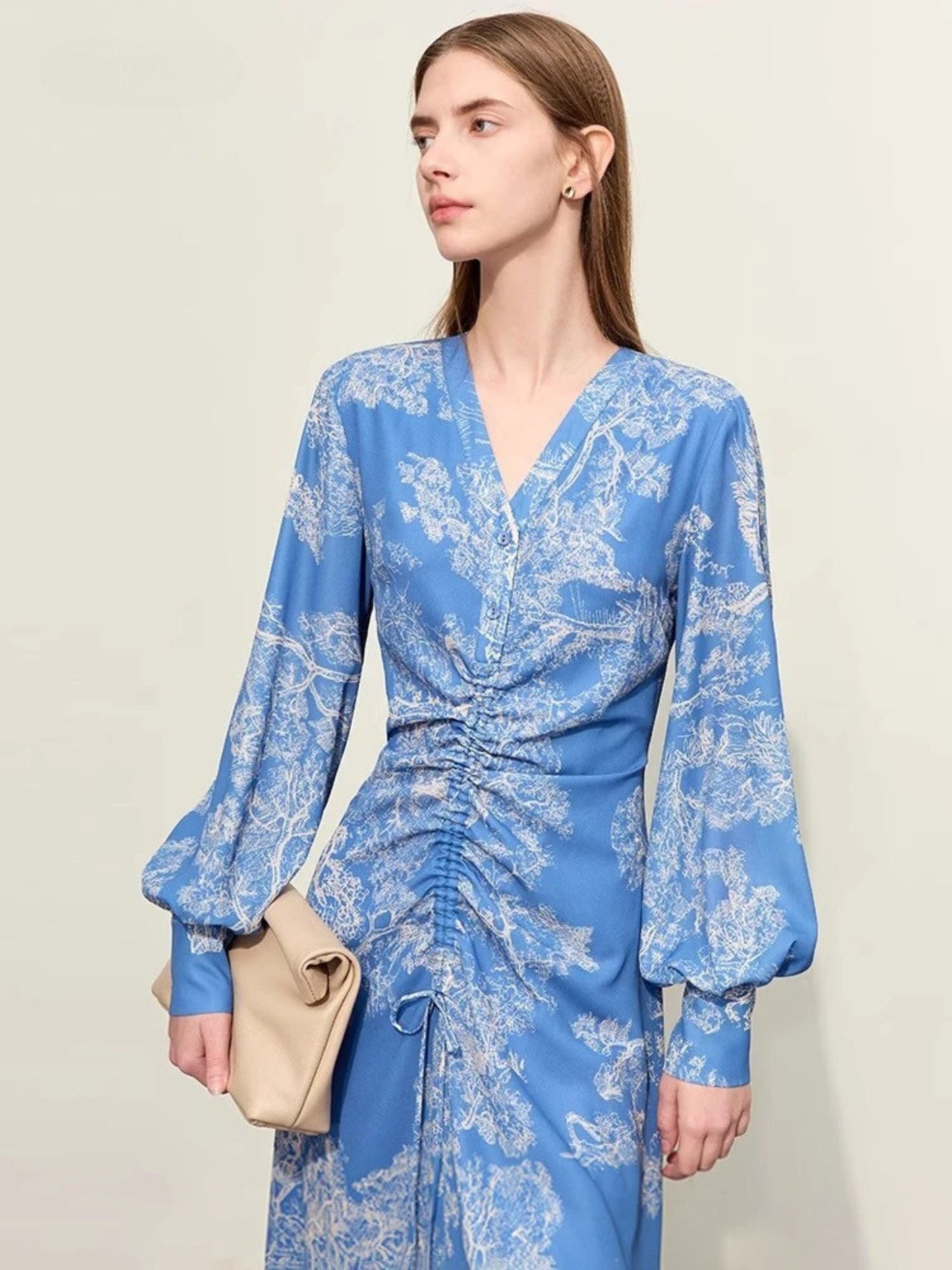 Close up view of blue floral wrap midi dress with ruched front and long puff sleeves