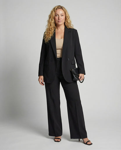 Woman wearing a black suit with a beige top on a gray background