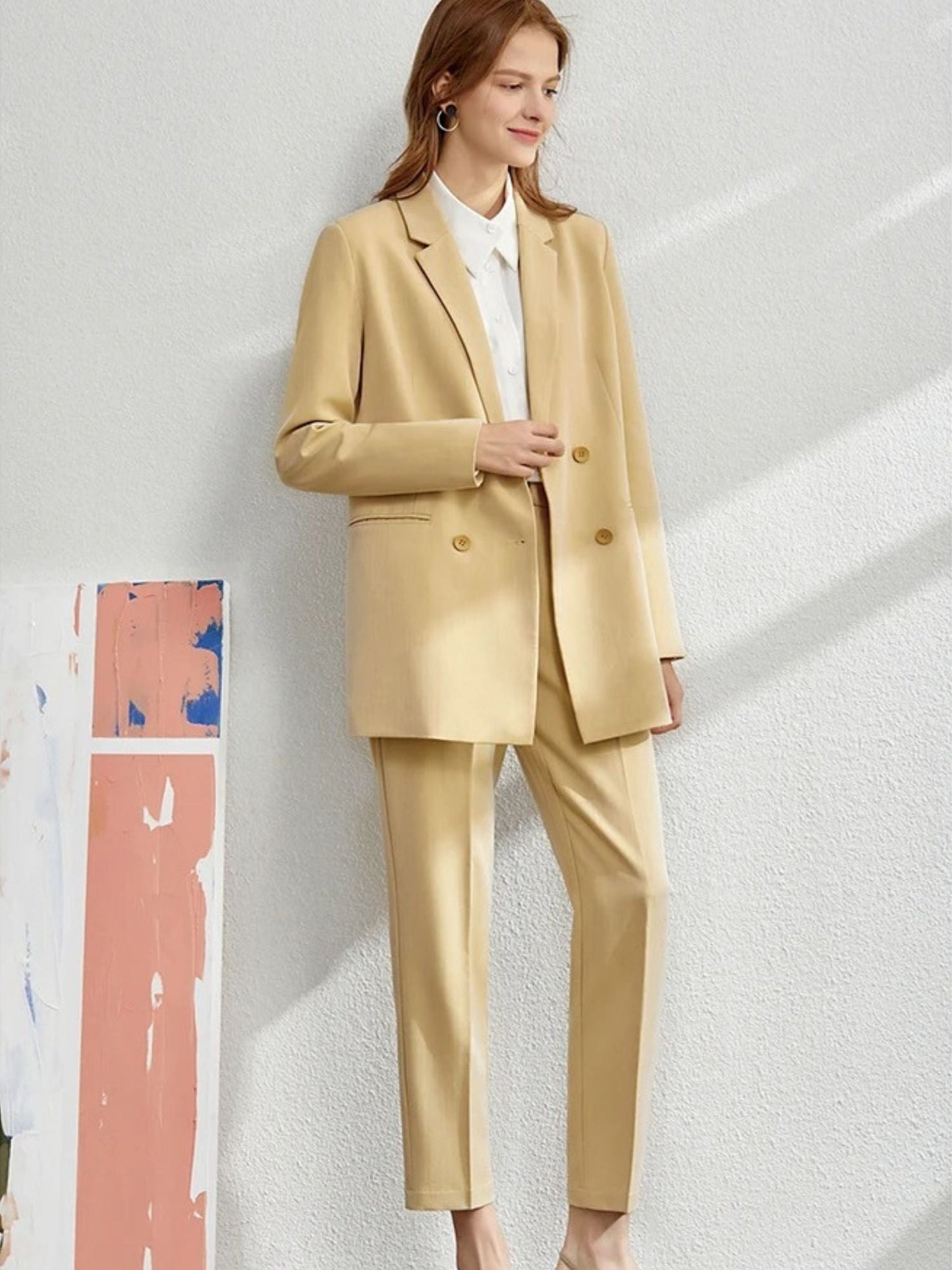 Woman wearing a light mustard yellow oversized blazer and matching tailored trousers with a white blouse