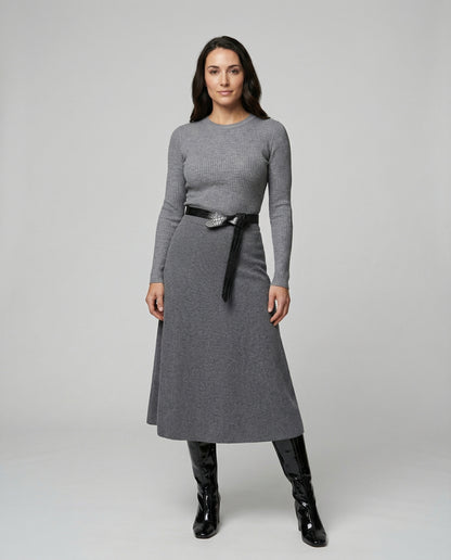 Woman wearing a gray dress with a black belt and black boots on a white background