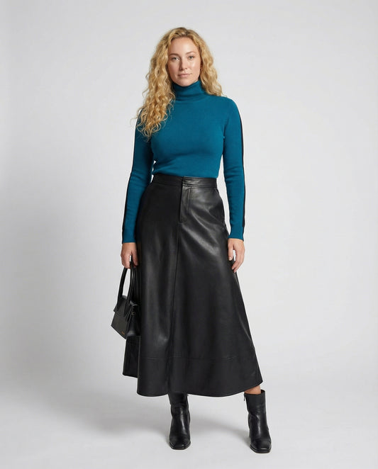 Woman wearing a teal turtleneck and black leather skirt on a white background