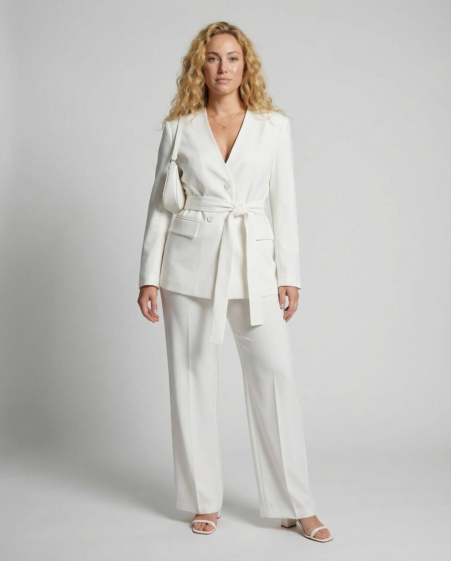 Woman wearing a white suit with a belt on a gray background