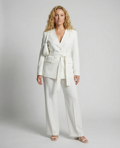 Woman wearing a white suit with a belt on a gray background