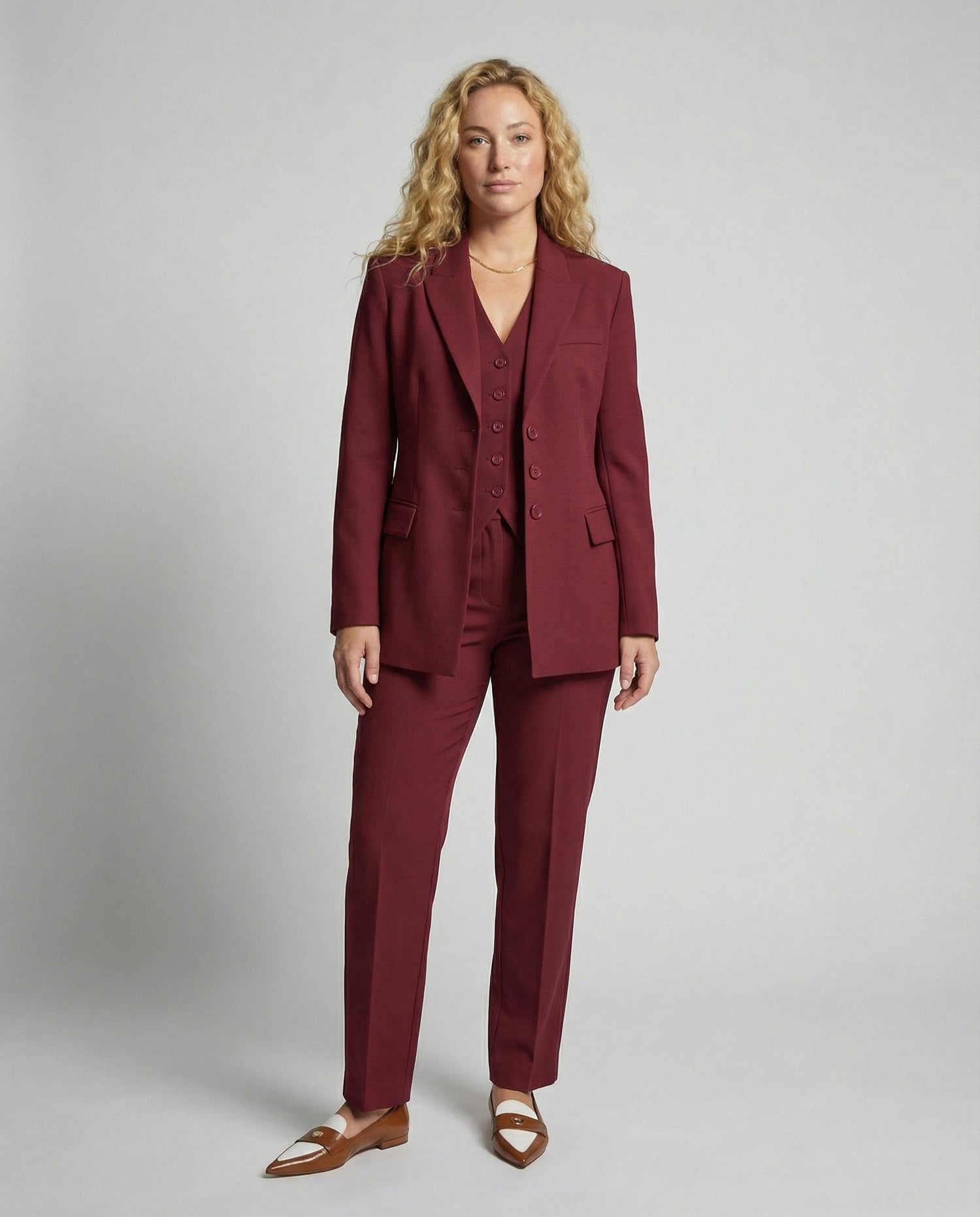 Woman wearing a burgundy suit against a plain background