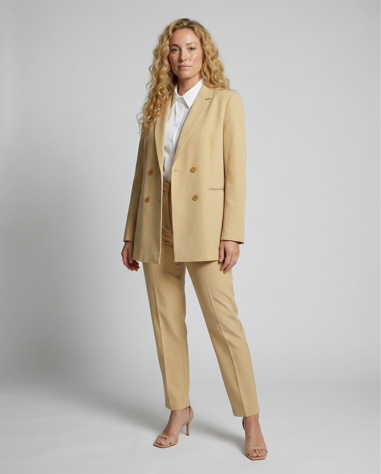 Woman wearing a beige suit with a white shirt on a plain background