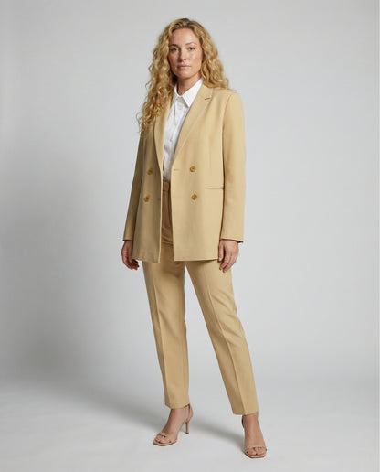 Woman wearing a beige suit with a white shirt on a plain background