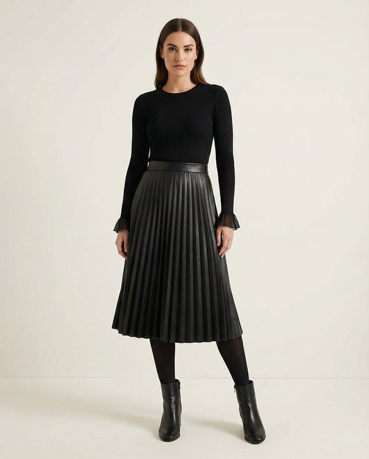 Woman wearing a black pleated skirt and black top on a white background