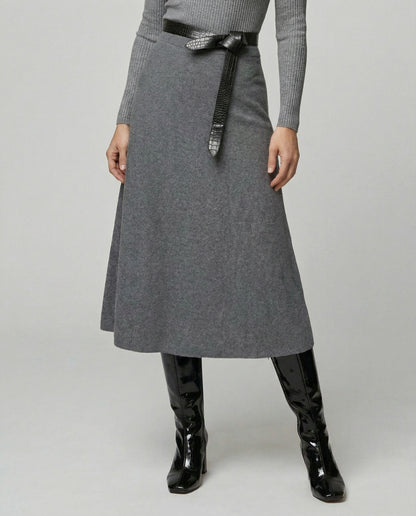Person wearing a gray skirt with a black belt and black boots on a light gray background