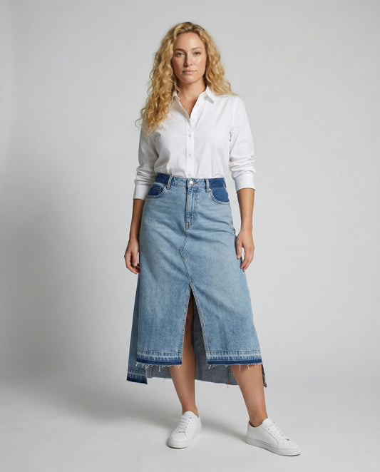 Woman wearing a white shirt and blue denim skirt on a gray background