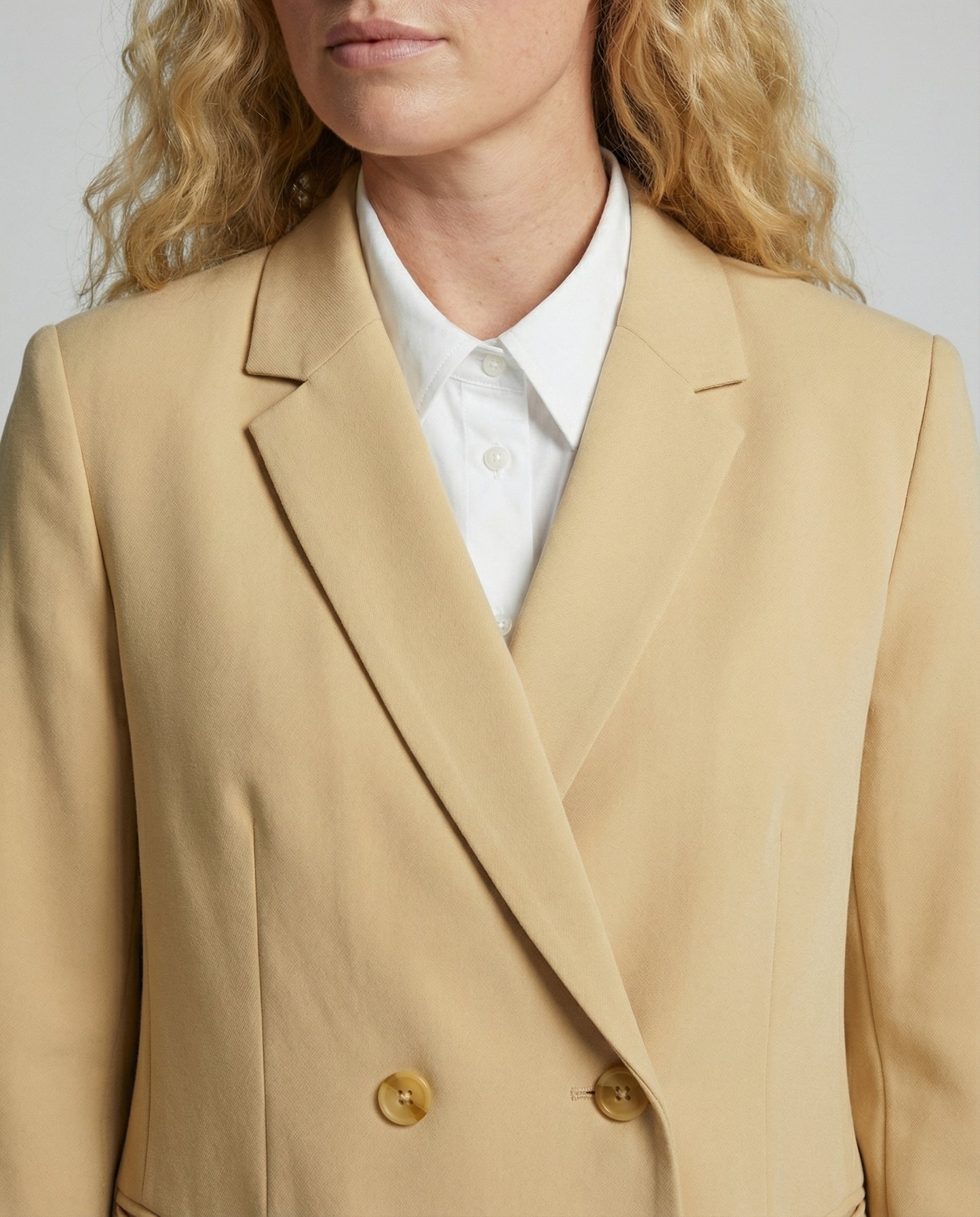 Beige blazer worn by a person with a plain background