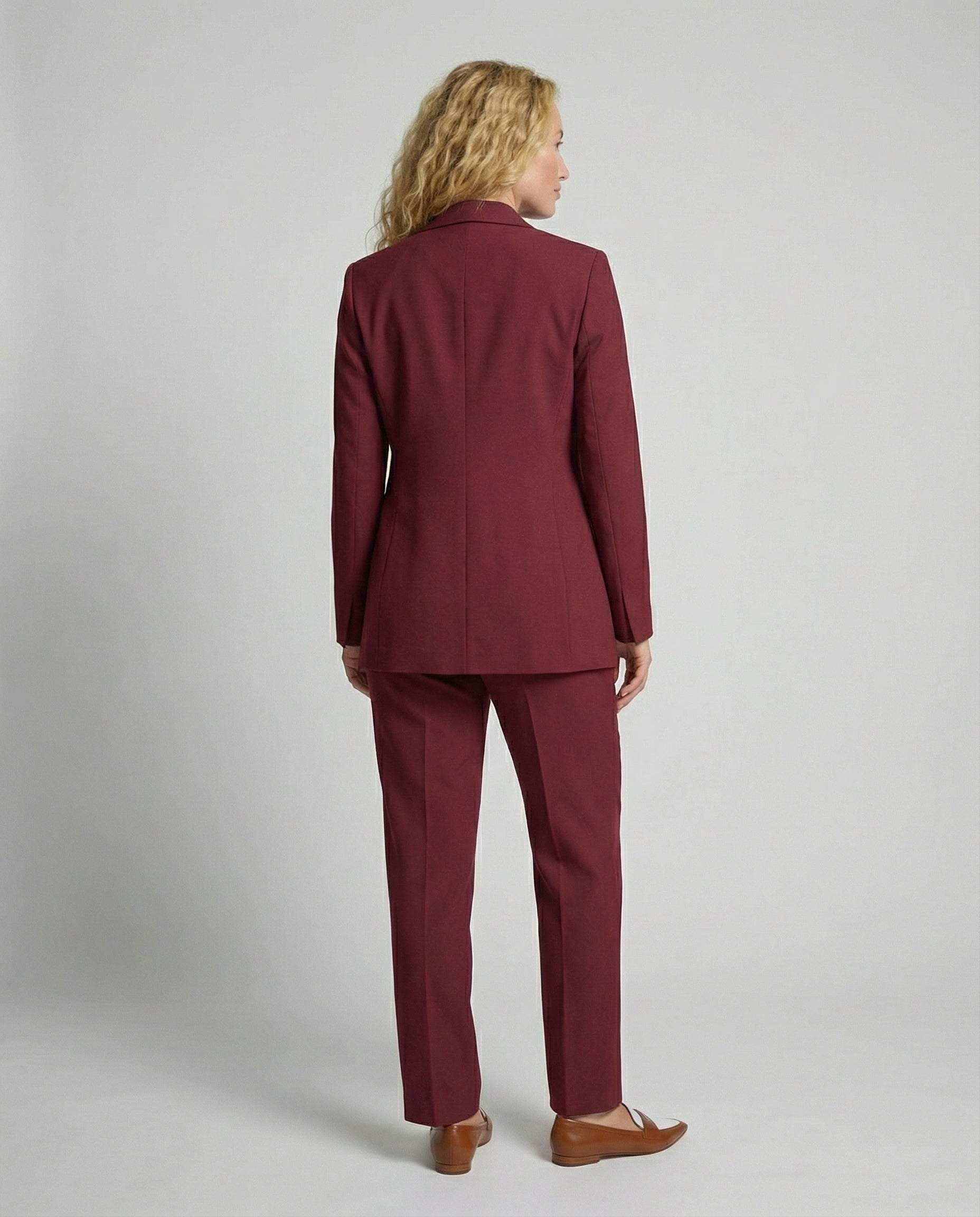 Woman wearing a burgundy suit against a plain background