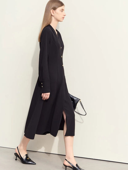 Model walking in black midi dress with V-neckline, long sleeves, and flared hem. Carrying black handbag