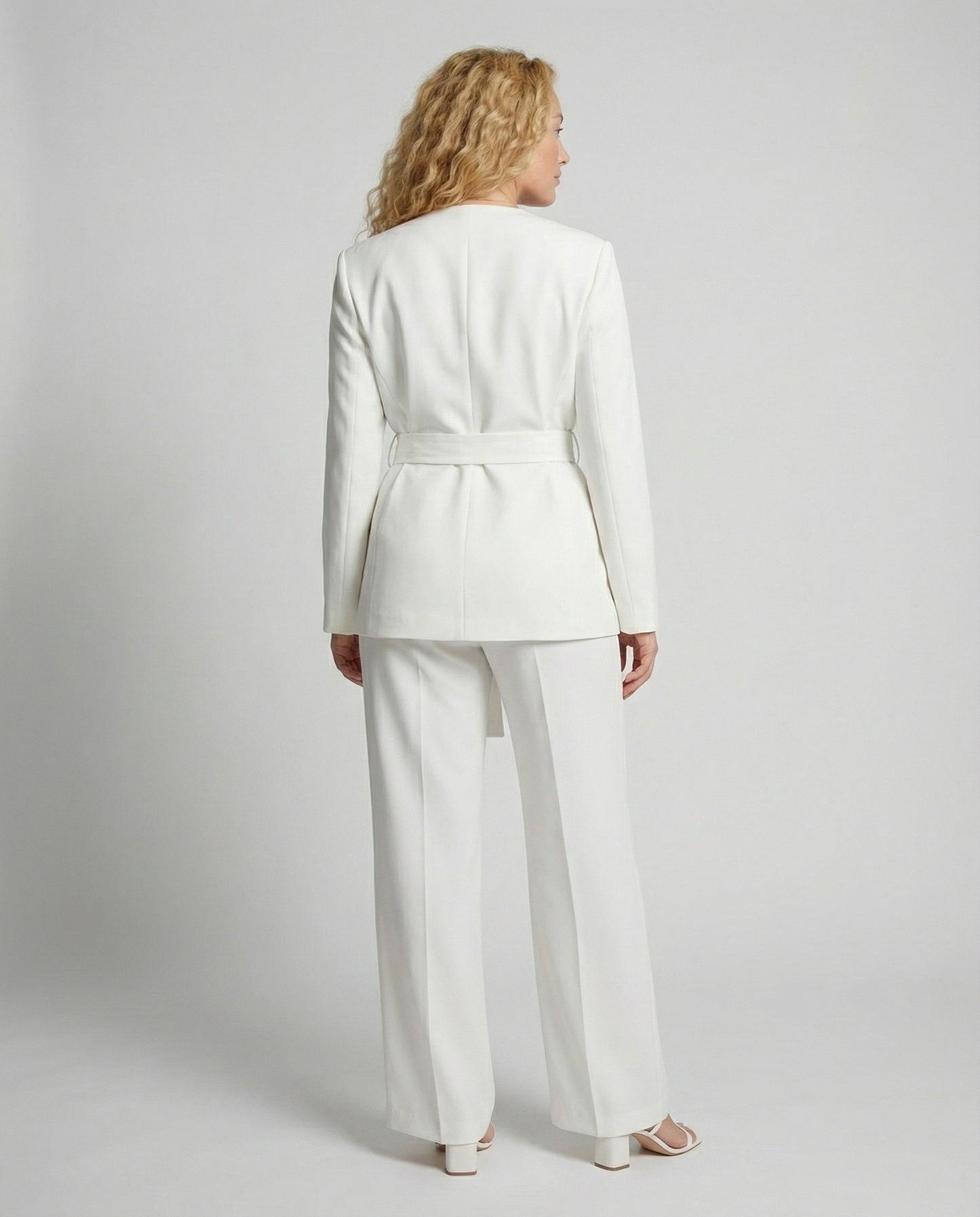 Woman wearing a white suit on a plain background