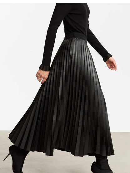 Walking side view of black faux leather pleated midi skirt showcasing flow and movement