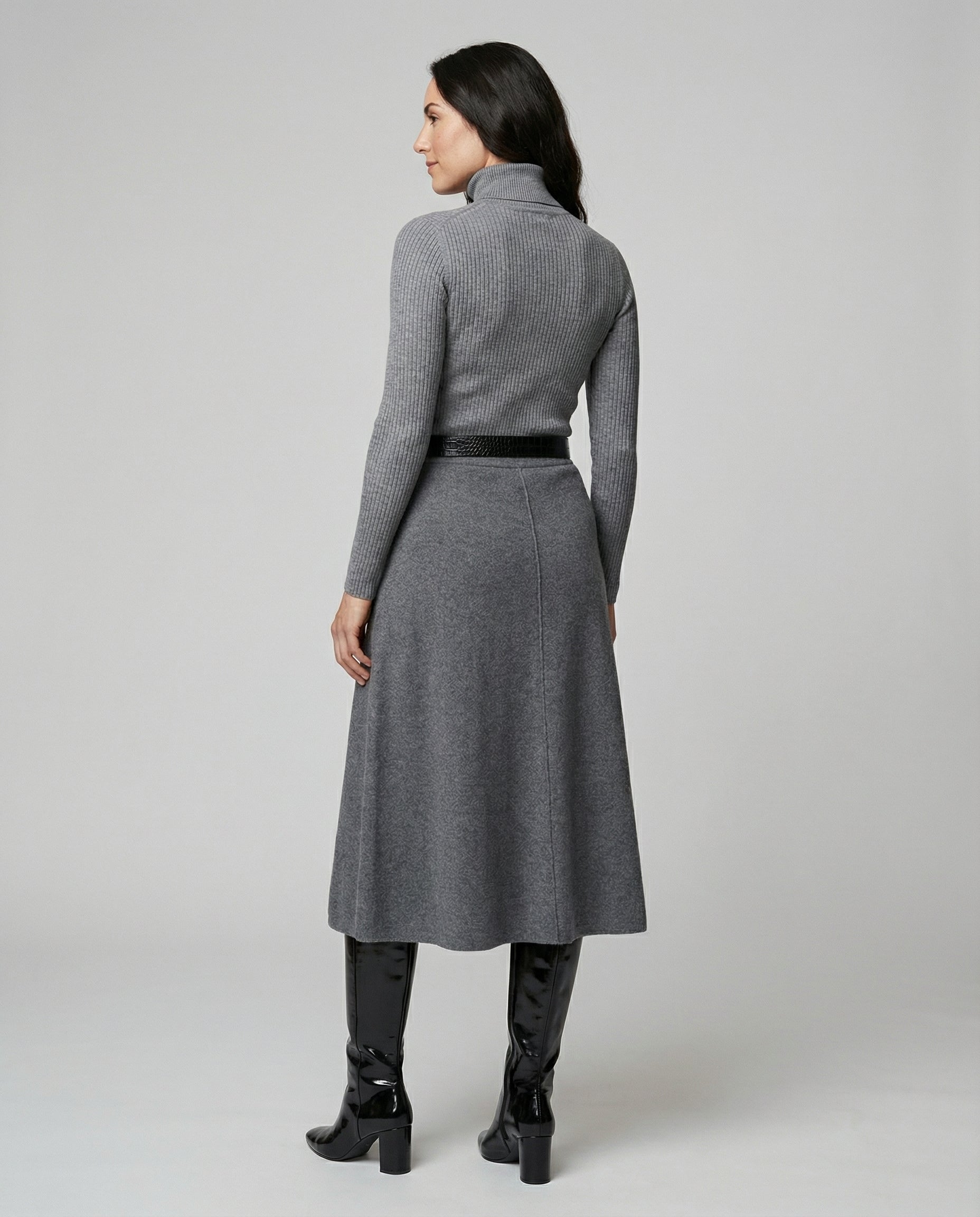 Woman wearing a gray dress with a belt on a plain background