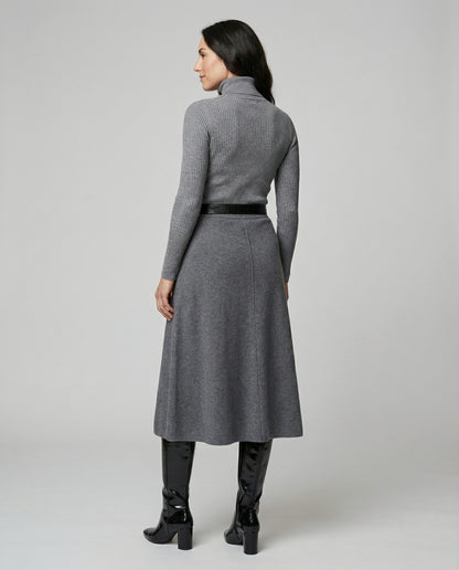 Woman wearing a gray dress with a belt on a plain background