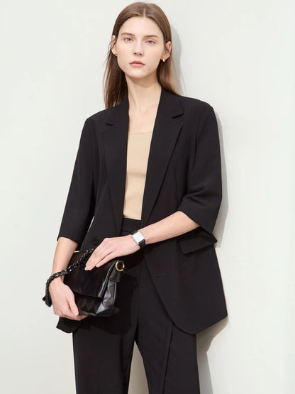 Close-up front view of woman in black elbow-length blazer and matching trousers with black accessories