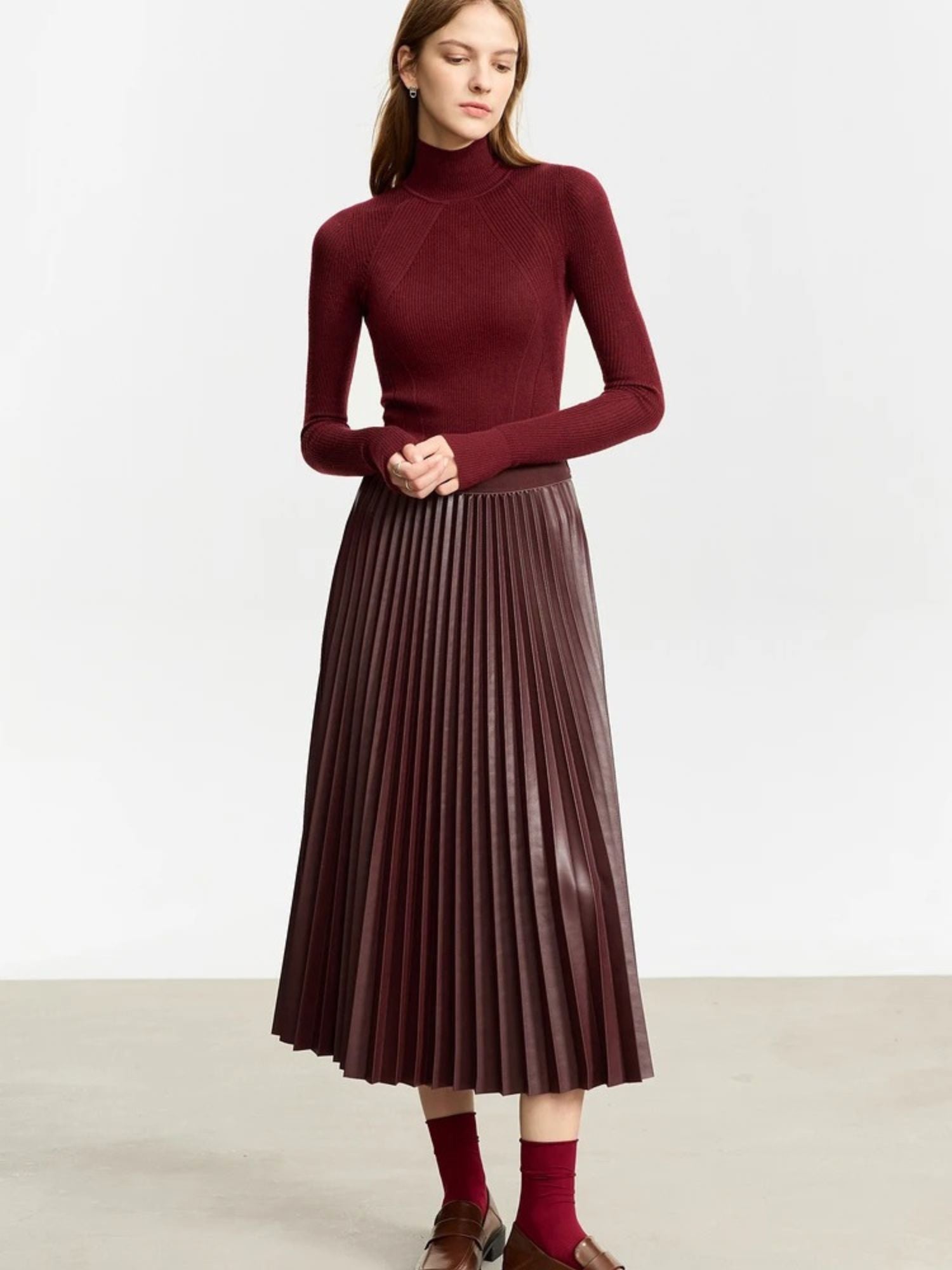 Front view of burgundy faux leather pleated midi skirt styled with burgundy long-sleeve top