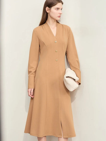 Three-quarter view of camel midi dress with belted waist and relaxed fit, model holding white handbag