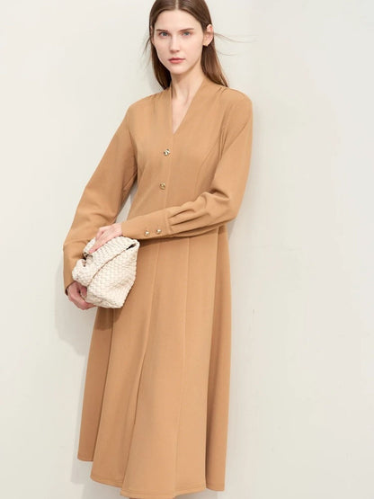 Camel-colored long-sleeve midi dress with button-front closure and relaxed fit, paired with white handbag and neutral shoes