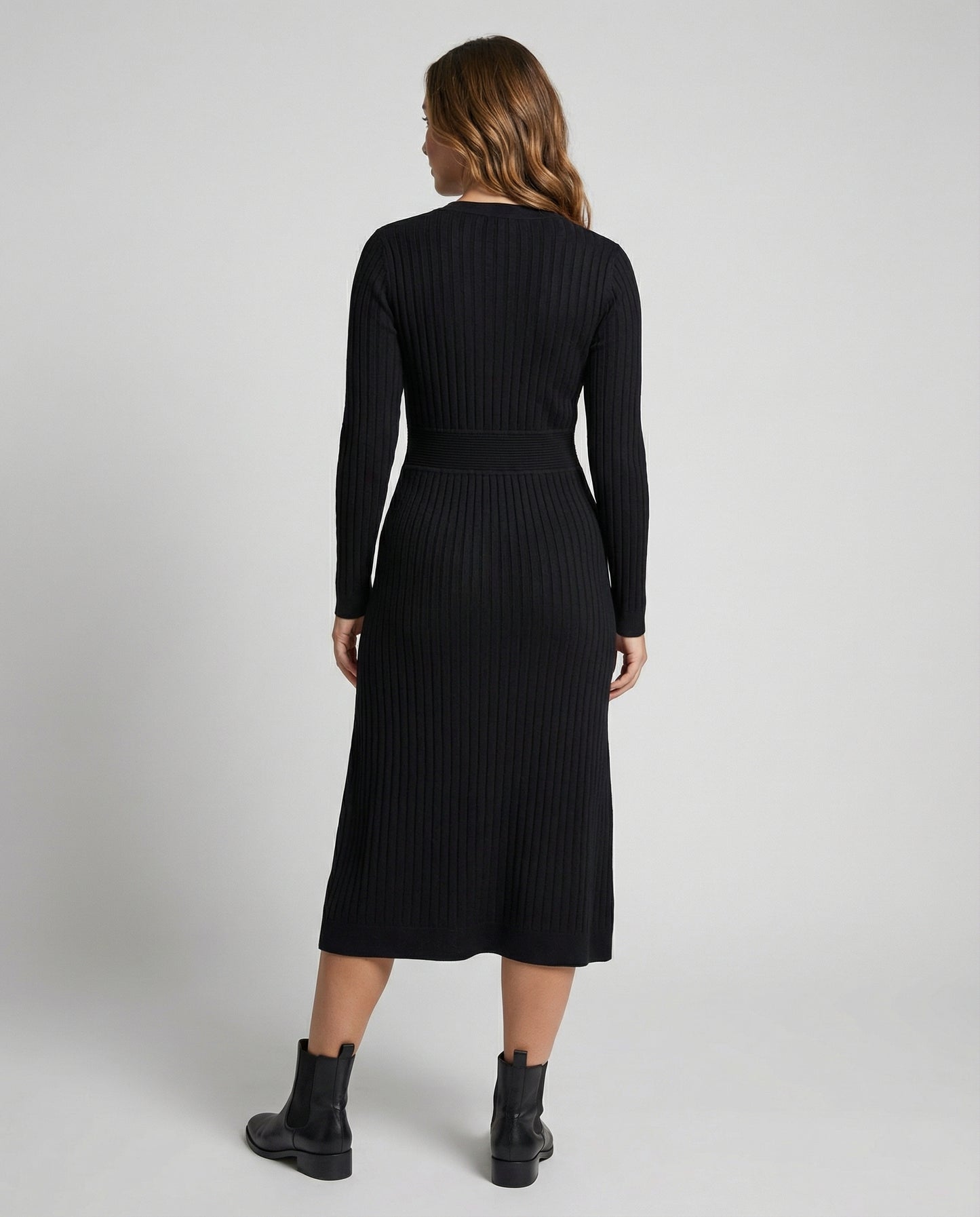 Woman wearing a black ribbed dress with long sleeves on a white background
