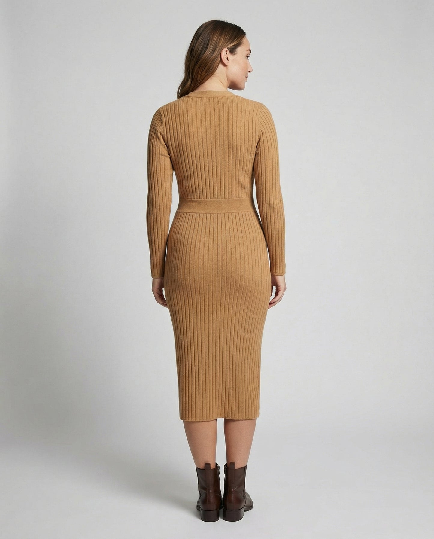 Woman wearing a brown ribbed dress on a plain background