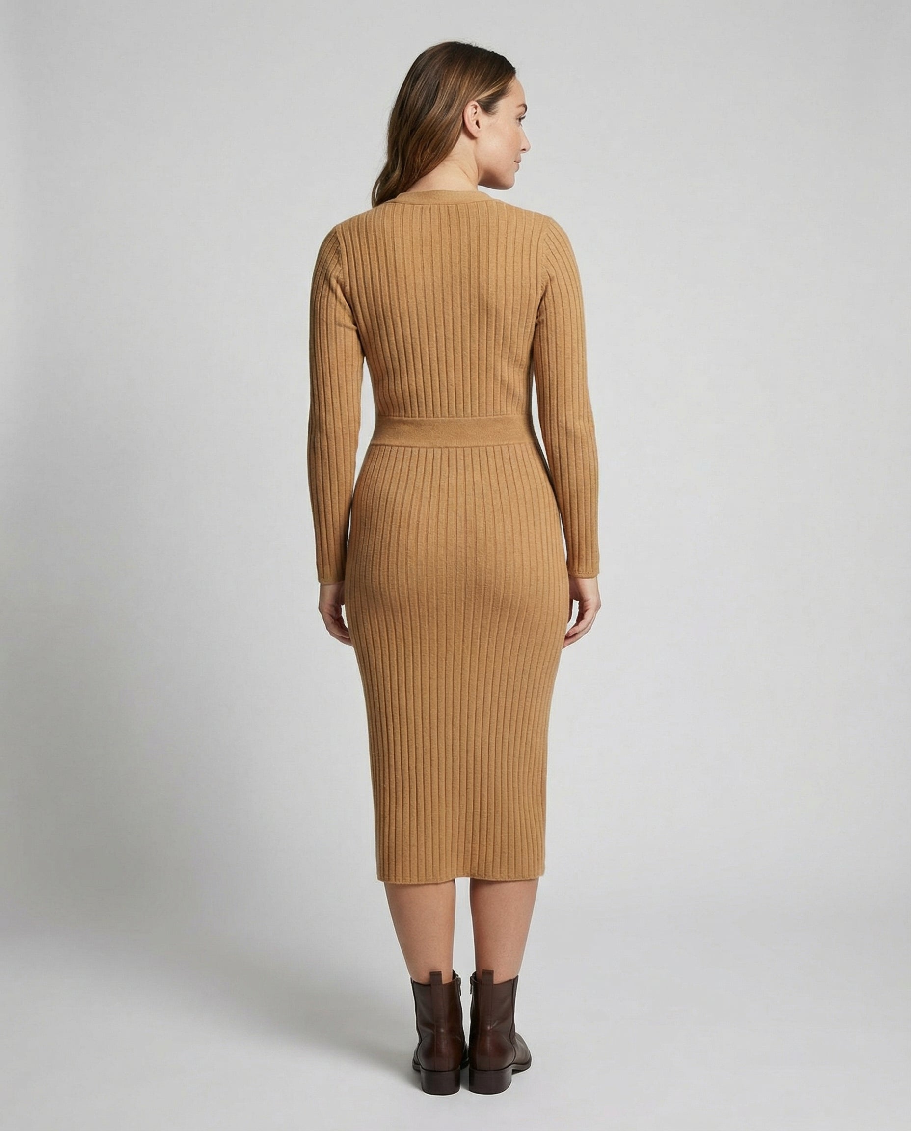 Woman wearing a brown ribbed dress on a plain background