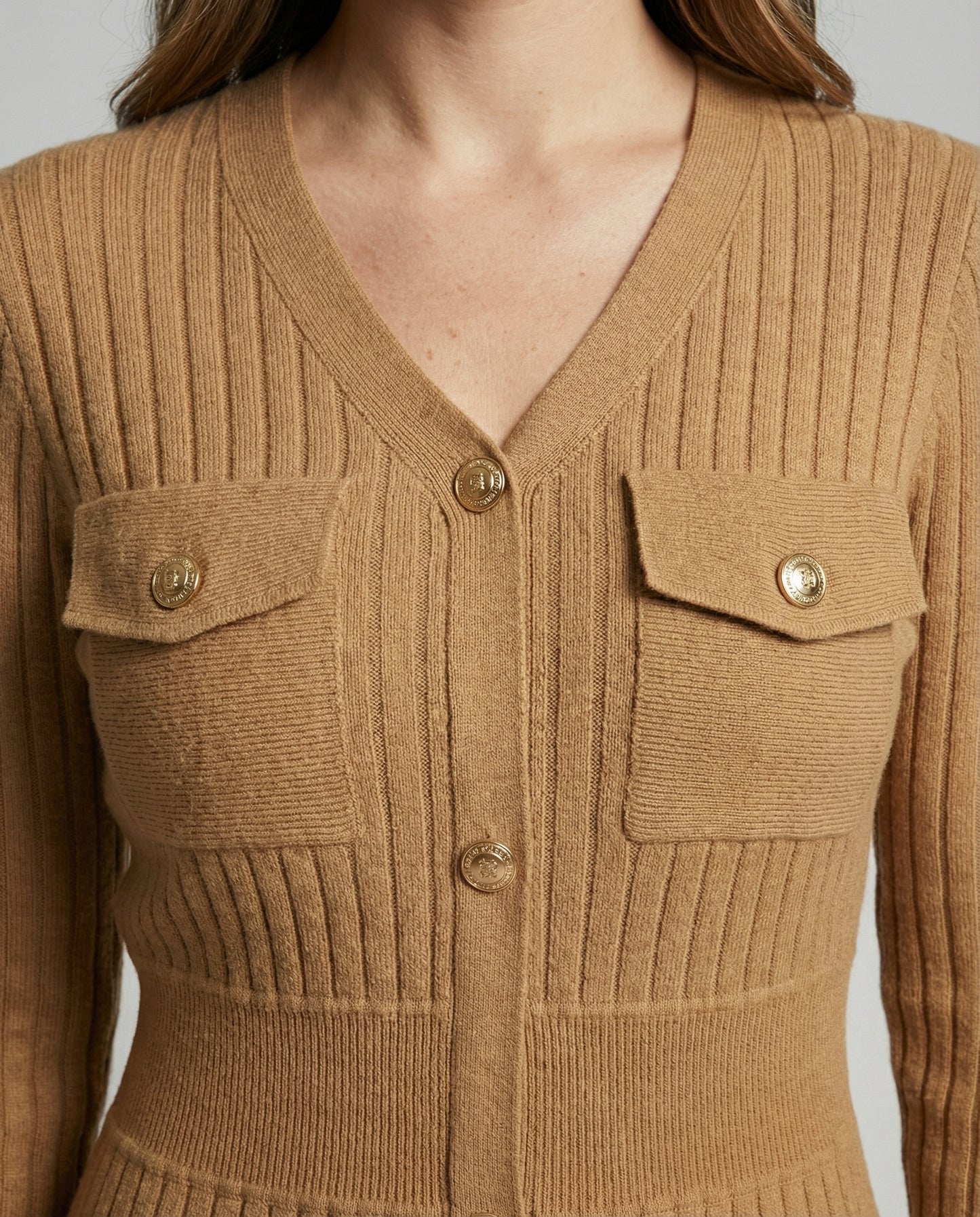 Close-up of a brown ribbed knit cardigan with button details.