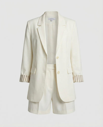 White blazer with striped cuffs on a light gray background
