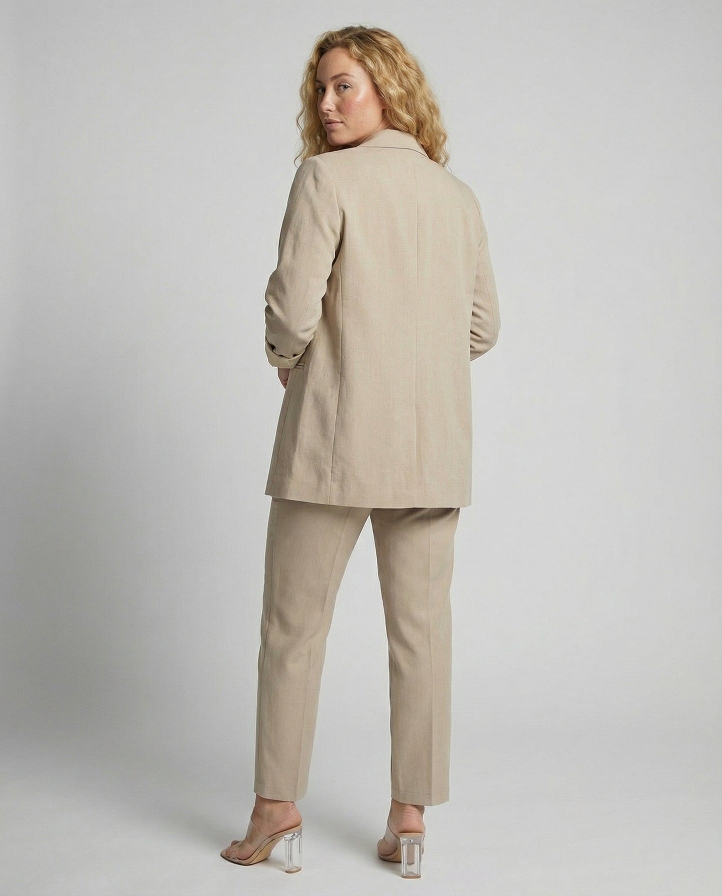 Woman wearing a beige suit against a plain background