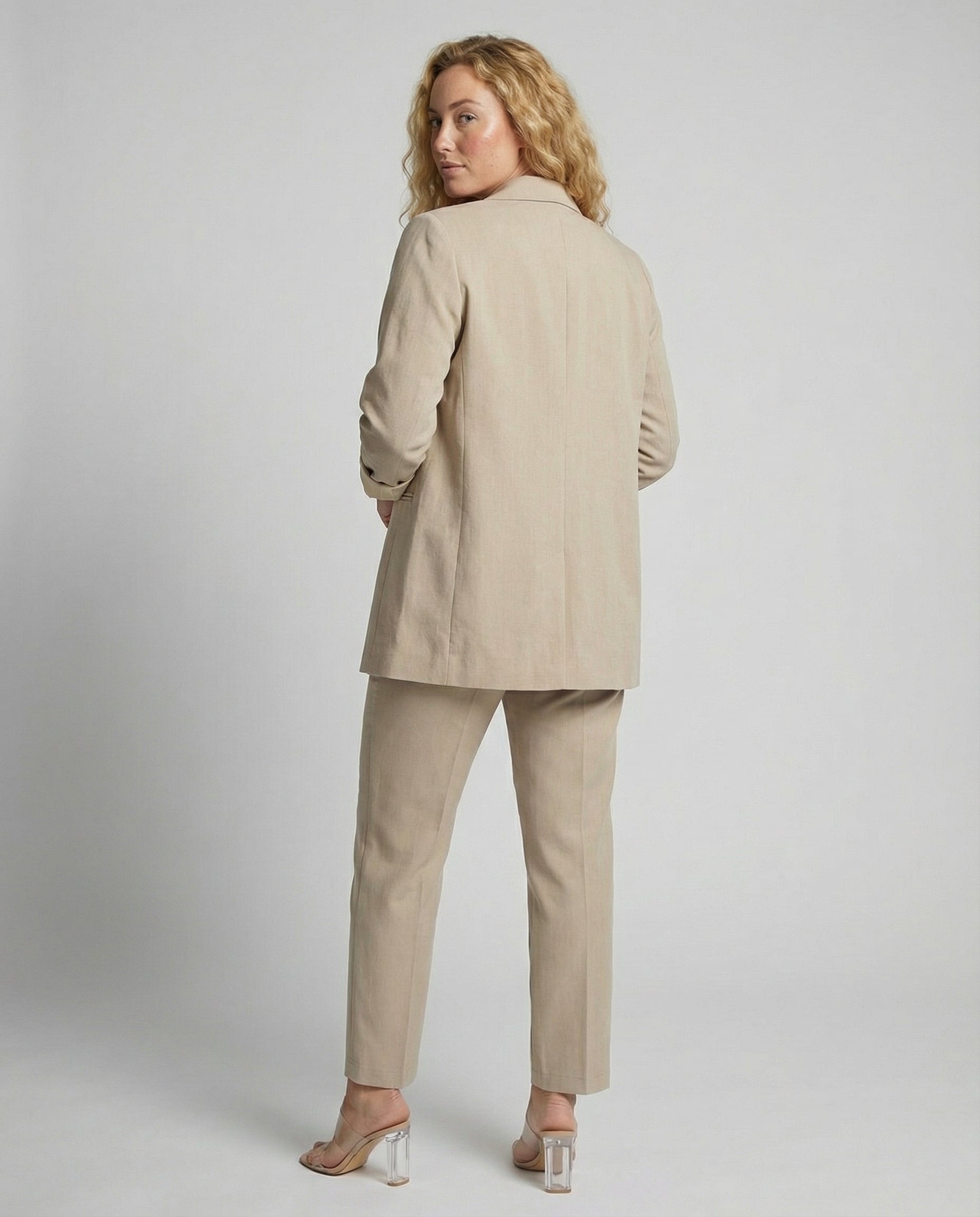 Woman wearing a beige suit against a plain background
