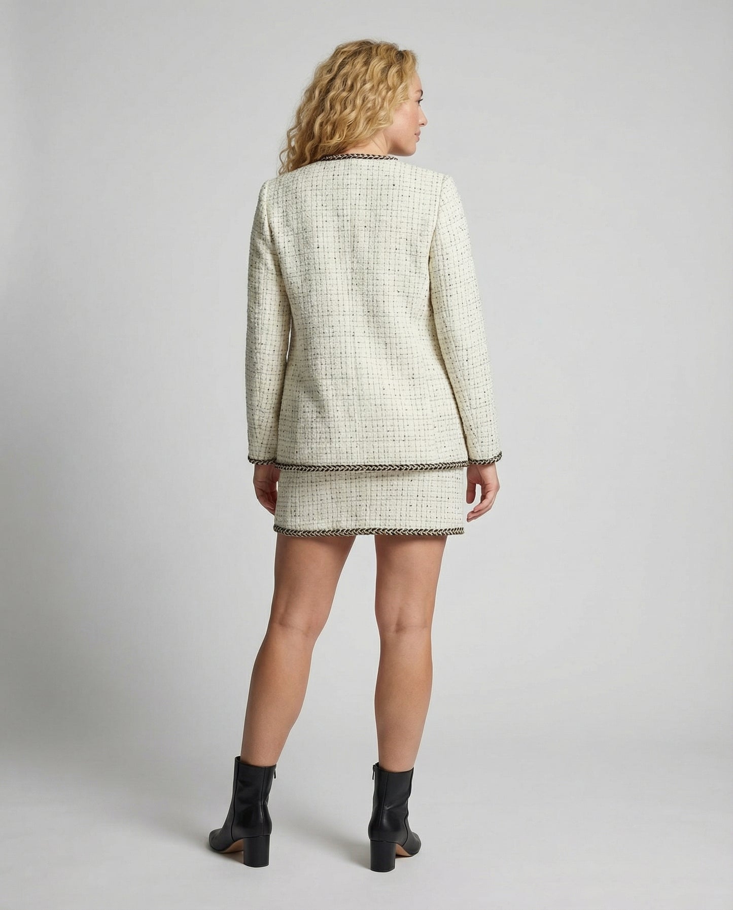Woman wearing a tweed jacket and skirt set on a plain background